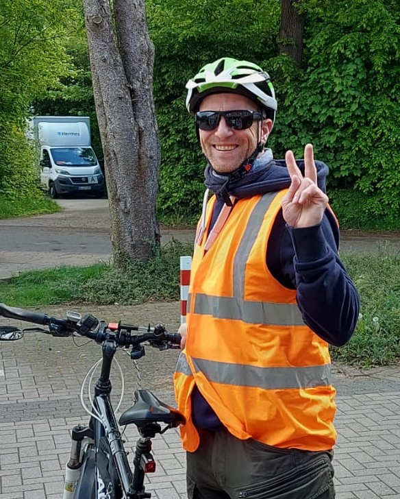 Ein Bild von Rainer, mit Sonnenbrille Fahrradhelm und orangener Warnweste